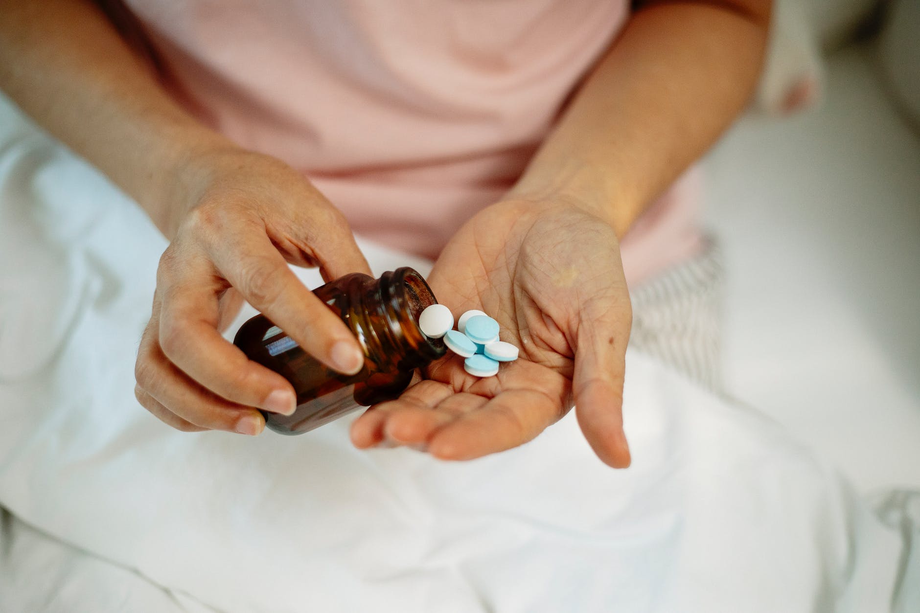 woman taking pills from jar on hand